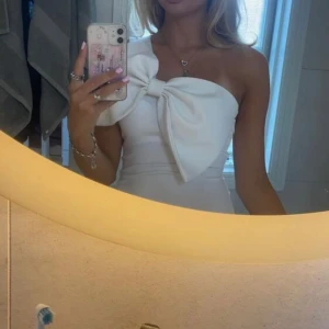 Vit oneshoulder body med stor rosett - Bodyn är aldrig använd då jag råkade beställa två stycken.                                                        Supersnygg vit topp med one shoulder och en stor rosett framtill. Tight passform som framhäver figuren och ger en trendig look. Perfekt för dig som vill sticka ut och älskar statement-detaljer. Mjuk och stretchig i materialet.