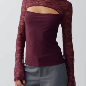 Vinröd spetsblus med cut out - Supersnygg vinröd blus från Gina tricot med transparent spets upptill och på ärmarna. Toppen har lång ärm, cut out-detalj över bröstet och en tight passform. Perfekt för dig som vill sticka ut med en unik och trendig look. Slutsåld och kommer aldrig tillbaka