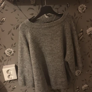 Grå stickad tröja från 157, S - Mysig grå stickad tröja från 157 i storlek S. Tröjan har en avslappnad passform med bred halsringning och trekvartsärmar. Perfekt för lager-på-lager och chill dagar. Enkel och stilren design som funkar till det mesta.