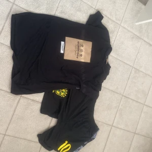 Svart Burberry t-shirt med tryck - Svart t-shirt från Burberry med ett stort beige tryck på bröstet där det står Burberry och har logga. Klassisk passform och rund halsringning. Perfekt för dig som vill ha en stilren men ändå lyxig look.