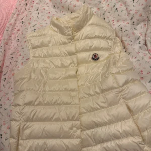 Vit dunväst från Moncler - Säljer nu min kära moncler väst då den ej kommer tilll användning så som jag trott. Köpt för 6000kr nypris men säljer för 3500kr eller billigare vid snabb affär! Inga defekter eller liknande. Passar S/M. Tvättas såklart innan jag postar💕💕