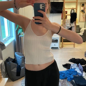 Ribbad vit linnetopp från H&M - Säljer en ribbad vit linnetopp från H&M i storlek XS. Toppen är croppad med smala axelband och har en snygg v-ringning. 