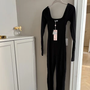 Svart långärmad jumpsuit - Oh Polly - Supersnygg svart långärmad jumpsuit från Oh Polly med fyrkantig urringning och figurnära passform. Storlek uk 4 us 0 (XXS)