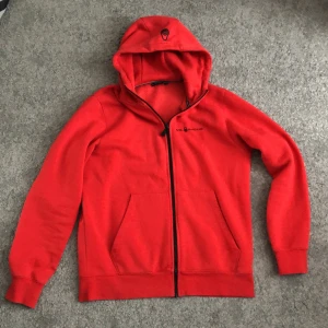 Röd hoodie från Sail Racing, storlek L passar M - röd hoodie från Sail Racing med svart dragkedja och huva. Tröjan har två fickor framtill och diskret logga på bröstet. Väldigt bra skick har tvättat den några gånger bara. Storleken är L men den är liten i storleken så passar M också.