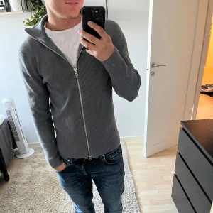 Grå ribbad kofta från Ljung - Säljer en stilren grå ribbad kofta från Ljung by Marcus Larsson i storlek S. Säljer på grund av att den inte kommer till användning.