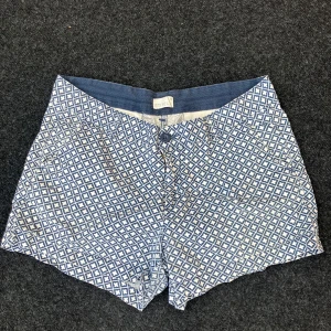 Blåvita mönstrade shorts från Etirel - Snygga blåvita shorts från Etirel med ett rutigt mönster och klassisk passform. Perfekta för varma dagar, med knapp och dragkedja framtill. Lätta och sköna att bära, passar till både t-shirt och linne.