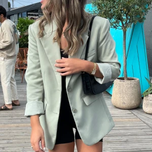 Grön kavaj från Gina Tricot XS - Stilren grön kavaj från Gina Tricot med klassisk krage, två knappar framtill och fickor med lock. Rak passform och helfodrad insida. Perfekt för en clean och trendig look. Använd fåtal gånger så bra skick