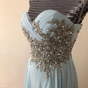 Ljusblå långklänning med paljetter - Drömmig ljusblå långklänning med axelbandslös överdel och vackra silverfärgade paljetter över byst och midja. Klänningen har svepande kjol i tunt tyg som ger en elegant känsla. Perfekt för bal eller student! Storlek s. 