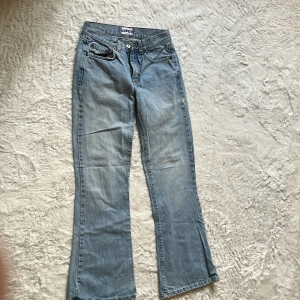 Bootcut jeans från Vila, ljusblå - Ljusblå bootcut jeans från Vila, modell Barbara Trousers. Klassisk femficksdesign med snyggt slitna kanter nertill för en avslappnad vibe. Jeansen har normal passform och är tillverkade i mjukt denimtyg som ger en skön känsla hela dagen.