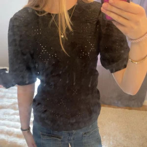 Svart blus med puffärm från Object - Säljer en svart blus från Object med korta puffärmar och broderade hål som ger en snygg och luftig känsla. Är i storlek S men passar även om man är xs.