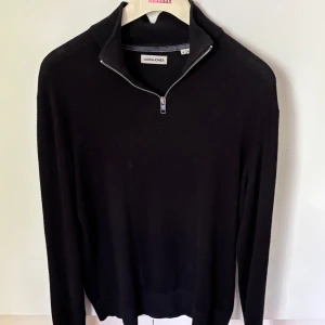 Svart half zip tröja Jack & Jones - Svart långärmad tröja från Jack & Jones med hög krage och half zip-dragkedja. Enkel och stilren design, perfekt till jeans eller chinos. Mjuk och skön känsla, passar dig som gillar klassiska basplagg.