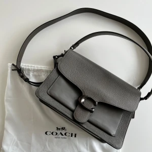 Coach tabby bag - Snygg grön grå tabby väska från Coach med justerbar rem och stilren design. Väskan har ett stort fack, lock med metallspänne och diskreta detaljer. det finns två justerbara remmar och det är super små märken på det större facket som ej syns när väskan är stängd. Ny pris: 6000-5000