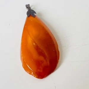 Bärnstenshänge med silverdetalj - Unikt hänge i droppformad bärnsten med varm orange ton. Upphängningen är i silverfärgad metall med snyggt bladmotiv. Perfekt att hänga på en kedja för en cool och naturlig look.