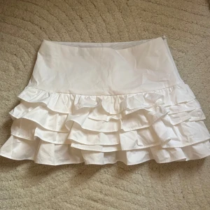 Vit volangkjol med shorts från Zara - Supersöt vit kort kjol med volanger och inbyggda shorts! Använd endast en gång så i nyskick. 🌸