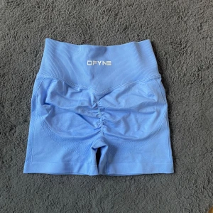 Blå Impact träningsshorts - Snygga ljusblå tränings-shorts med hög midja och ribbad linning. Shortsen har scrunch-detalj bak för extra form och är tillverkade i ett stretchigt syntetmaterial som sitter tight och bekvämt. Perfekta för gymmet eller löprundan.