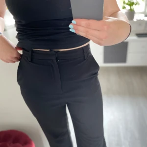 Svarta kostymbyxor från GinaTricot - Snygga svarta kostymbyxor med raka ben och bekväm passform. Byxorna har hysk- och hakstängning samt dold dragkedja framtill. Klassisk look med fickor fram och passpoalfickor bak. Perfekta för en clean och stilren outfit. De är sparsamt använda och fint skick. Storlek S