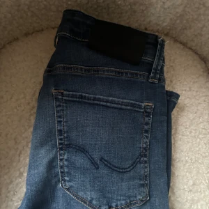 Mörkblå skinny jeans Jack and Jones  - Snygga mörkblå skinny jeans med klassisk femficksdesign och diskreta sömmar. Jeansen har en smal passform och är tillverkade i stretchigt denimtyg för en bekväm känsla. Perfekta till sneakers eller boots.