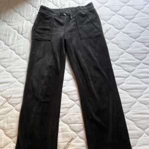 Svarta mjukisbyxor Juicy Couture S - Svarta mjukisbyxor från Juicy Couture i storlek S. Byxorna har raka ben, bred resår i midjan med snörning och två stora fickor fram och bak (med knappar). Mjukt och skönt material med diskret logga på ena fickan. Matchande kofta säljs till med paket pris såklart (800kr)