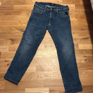 Blå jeans från Replay - Snygga blå jeans från Replay med klassisk femficksdesign och raka ben. Jeansen har normal passform och är tillverkade i slitstarkt denimtyg. Perfekta för dig som gillar en tidlös och stilren look. storlek 30 längd 29