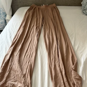 Beiga wide byxor från Bubbleroom XS - Supersköna och luftiga beiga byxor från Bubbleroom i storlek XS. De har en bred resår i midjan och riktigt vida ben för en chill och trendig look. Perfekta till sommaren eller när du vill ha en avslappnad stil.