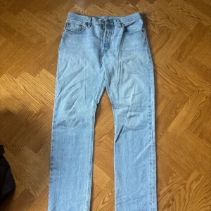 Levi's 501 ljusblå jeans straight fit - Säljer ett par klassiska Levi's 501 jeans i ljusblå tvätt. Modellen är straight fit med hög midja och fem fickor. Jeansen har den ikoniska läderpatchen bak och är tillverkade i robust denim. Perfekta till sneakers eller boots.