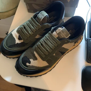 Valentino Garavani Rockrunner sneakers - Snygga Valentino Garavani Rockrunner sneakers i grön, beige och svart camouflage. Ovandel i mesh och skinn, med coola detaljer och grov sula. Klassisk snörning och ikonisk design som sticker ut. Perfekta för dig som vill ha något unikt och trendigt.