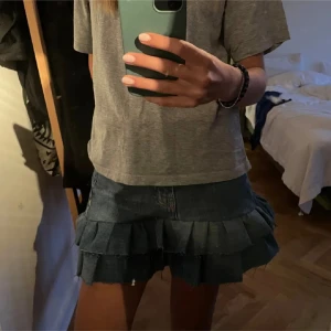 Jeanskjol med volanger - Säljer en snygg kort jeanskjol med dubbla volanglager. Kjolen har en klassisk blå denimfärg och råa kanter för en cool vibe. Perfekt att styla med en enkel t-shirt eller hoodie för en avslappnad look. Midjemått 72❤️