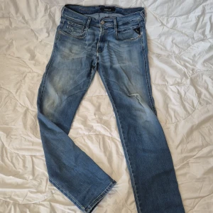 Replay Anbass ljusblå jeans - Säljer ett par Replay Anbass jeans i ljusblå tvätt med slitningar och snyggt distressed look. Klassisk femficksmodell, normal passform och medelmidja. Jeansen är tillverkade i stretchigt denim för extra komfort och har Replay-logga på fickan.