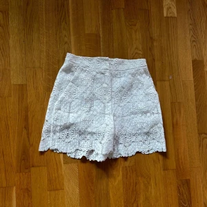 Vita spetsiga shorts från Maje - Superfina vita shorts från Maje med vacker spets och broderade detaljer. De är högmidjade och har en feminin, elegant look med vågig kant nertill. Perfekta för sommarens varma dagar och ger en riktigt fräsch vibe.