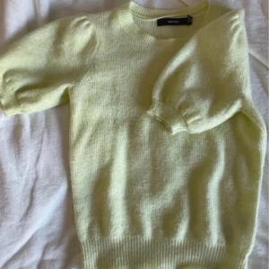 Ljusgul stickad tröja Vero Moda - Superfin ljusgul stickad tröja från Vero Moda med puffiga korta ärmar och rund halsringning. Mjuk och skön, perfekt för vår och sommar. Enkel att styla med både jeans och kjol för en fräsch look.