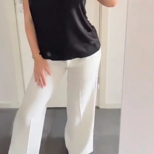 Vita vida kostymbyxor - Snygga vita kostymbyxor med vid passform och pressveck. Byxorna har hög midja och är perfekta för en clean och stilren look. Passar grymt till både sneakers och klackar. 