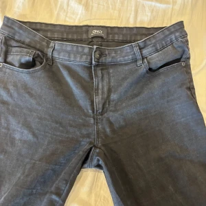 Mörkgrå jeans från ONLY - Snygga mörkgrå jeans från ONLY med klassisk femficksdesign och knappgylf. Jeansen har en rak passform och är tillverkade i mjukt bomullsmaterial med lite stretch för extra komfort. Perfekta till en avslappnad streetstyle-look.