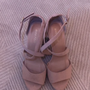 Nude/rosa klackar/sandaletter från Anna Field - Snygga nude/rosa klackar/sandaletter från Anna Field med bred klack och öppen tå. Skorna har korsade remmar över foten och justerbart spänne vid ankeln. Använd 1 gång, lite slitage på undersidan men annars som nya, klacken är 10 cm hög