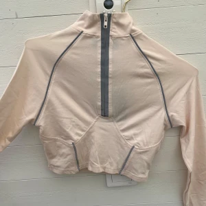 Rosa croppad half zip från Missguided - Snygg croppad tröja från Missguided x Sonia x Fyza i rosa med reflex detaljer. Prislappen kvar!