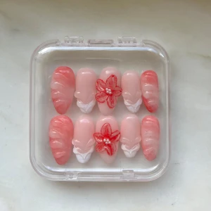 Handgjorda Press-on naglar 💗 - Säljer ett set press-on naglar i rosa och korall med 3D-blommor och vita detaljer. De har också andra typer av 3D designs. Naglarna är almond formade och kommer i en genomskinlig ask. Medföljer gör ett nagellim och en nailwipe. Perfekt för dig som vill ha snygga naglar snabbt! Tumme: 14mm, Pekfinger: 12mm, Långfinger: 13mm, Ringfinger: 10mm, Lillfinger: 9mm (måtten är på ett ungefär) 💕