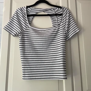 Randig ribbad topp från Gina Tricot - Säljer min fina svart och vit randiga topp från Gina Tricot i storlek M. Den är ribbad, har öppen rygg och en lite snurr detalj i nacken. 