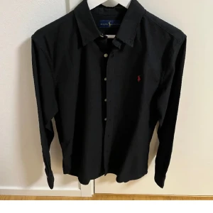 Svart skjorta från Ralph Lauren - Säljer min svarta Ralph Lauren skjorta då jag tröttnat på den. Fint skick utan tecken på användning. Kom gärna med prisförslag, priset är inte hugget i sten!