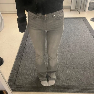 Grå bootcut jeans från Gina Tricot - Säljer ett par grå jeans från Gina Tricot i storleken 32. Jeansen har stretch, två fickor där fram och två där bak. Säljer dem då de är för långa för mig. Skulle passa alla mellan ca 163-167.
