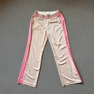 Rosa wide sidenbyxor från Gustav  - Älskar de här byxorna från Gustav med rosa detaljer och dragkedjor, men är tyvärr lite små för mig för att det ska vara fint. Byxorna har en loose fit och är tillverkade i ett mjukt, glansigt material som känns lyxigt. Perfekta för en chill och trendig look. Säljer dem för 10% av utsprungspriset nu, köpta för 1500 kr. 