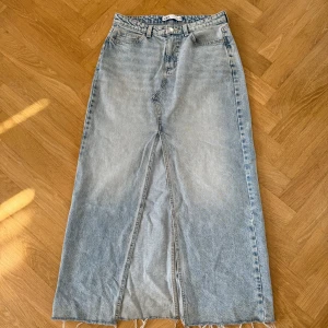 Ljusblå lång jeanskjol från Zara - Ljusblå lång jeanskjol från Zara med rå kant nertill. Kjolen har en slits framtill.