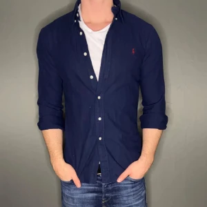 Mörkblå Ralph lauren skjorta - Hej säljer nu min fina Ralph lauren skjorta i storlek M. Den är i bra skick och kommer vara otroligt snygg nu i vår och framåt sommaren. Nypris cirka 1600kr! Vi kommer att sälja liknande produkter nu i vår och närmare sommar så glöm inte följa profilen!🌊🍾