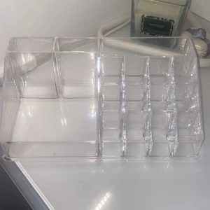 Transparent sminkförvaring i akryl - Snygg och praktisk sminkförvaring i genomskinlig akryl med flera fack i olika storlekar. Perfekt för att organisera läppstift, borstar, pennor och små sminkprodukter på sminkbordet. Stilren design som passar alla rum.