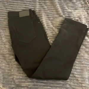 Svarta Jack & Jones jeans - Svarta slim fit jeans från Jack & Jones, modell Glenn. Klassisk femficksdesign med smal passform och normal midja. Snygga och stilrena byxor som passar till det mesta. Materialet är mjukt och stretchigt för extra komfort.