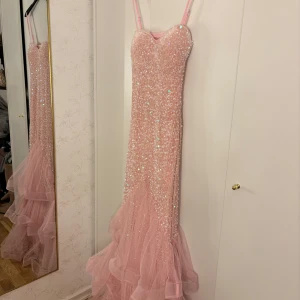 Rosa glittrig bal/festklänning - Säljer en fantastisk rosa långklänning med glittriga paljetter och volanger. Klänningen har smala axelband som är justerbara och öppen rygg. Den är använd en kväll men har inga synliga täcken på användning. Materialet är bra och den passar min bra i längden (är 1,70cm). Köpt av en annan säljare här på Plick. Vid frågor är det bara att höra av er!🩷Bilder är lånade men kan skicka nya!