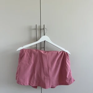 Rosa sportig kortkjol från SOC - Säljer en söt rosa kortkjol från SOC med sportig känsla. Kjolen har en enkel, slät framsida och lätt utställd baksida för extra rörelsefrihet. Perfekt för dig som gillar en aktiv stil och vill ha något bekvämt och snyggt.