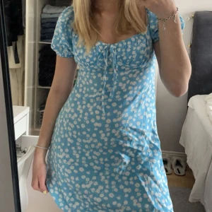 Blå klänning - Blå klänning med vita blommor. Från chiquelle i storlek S. Endast använd cirka 2 gånger så den är i bra skick!