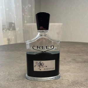 Creed Aventus 100ml parfym (75ml kvar) - Lyxig parfym från Creed Aventus, 100ml flaska men bara 75ml kvar. Flaskan är transparent med svart och silverdetaljer, och har en svart kork. Medföljer originalkartong och informationsblad. Doften är ikonisk och exklusiv, perfekt för dig som vill sticka ut med en klassisk och modern touch.
