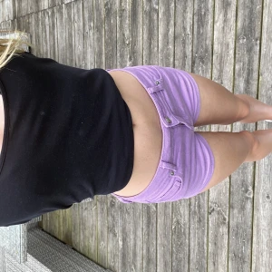 Lila jeansshorts från Divided - Snygga lila jeansshorts från Divided med klassisk femficksmodell, bälteshällor och knappstängning. Modellen är midwaist och har en tight passform som sitter riktigt snyggt. Perfekta för sommardagar när du vill sticka ut lite extra.