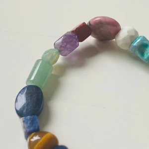 Färgglatt armband med ädelstenar - Unikt armband med pärlor i olika former och färger, gjorda av ädelstenar som ametist, tigeröga, turkos och rosenkvarts. Pärlorna är slipade i både runda och kantiga former och sitter på elastisk tråd. Perfekt för dig som gillar färg och boho-stil.