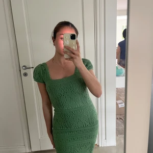 Grön stickad kortklänning med puffärm - Superfin grön stickad klänning med kort ärm. Klänningen har puffiga ärmar och ett snyggt hålmönster över hela plagget. Den sitter figurnära och slutar ovanför knäna. Köpt från NAKD och aldrig använd. Jättefin grön färg om modell passande till sommaren 